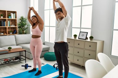 Genç Latin sporcu çift gülümseyerek evde mutlu bir antrenman yapıyor..