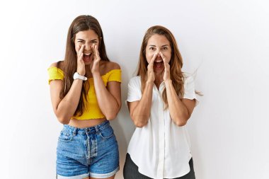 Anne ve kızı birlikte izole bir arka planda durarak elleri ağızda bağırarak bağırıyorlar. 