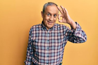 Gri saçlı, rahat tişörtlü, gülümseyen, el ve parmaklarıyla 