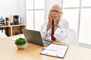 Ofiste çalışan kıdemli bir adam bilgisayar laptopu kullanıyor. Yorgun eller yüzünü, depresyonunu ve üzüntüsünü gizliyor. Problemlere kızıyor ve sinirleniyor. 