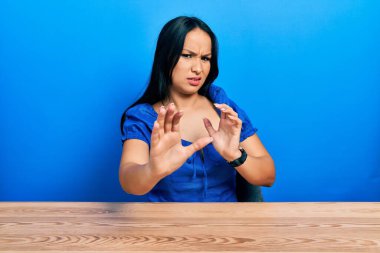 Burnuna piercing taktırmış güzel İspanyol bir kadın iğrenç bir ifadeyle masada oturuyor ve tiksinti dolu bir yüz ifadesi takınıyor çünkü tiksinti tepki veriyor. Eller havada. 