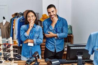 Perakende mağazasında çalışan ırklar arası genç insanlar kameraya bakıp kollarını kavuşturup, ellerini çeneye kaldırarak gülümsüyorlar. Olumlu düşünmek. 