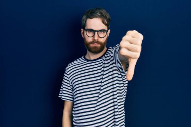 Sakallı, çizgili tişörtlü, gözlüklü, mutsuz görünen, reddedilmiş ve olumsuz jestli beyaz bir adam. kötü ifade. 