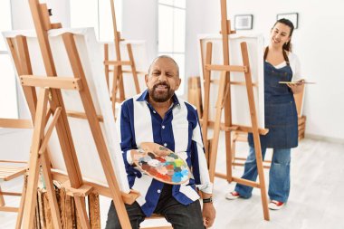 Sanat stüdyosundaki kıdemli sanatçı kameraya seksi bir ifadeyle bakıyor, neşeli ve mutlu bir yüzle.. 
