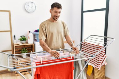 Genç İspanyol adam çamaşırhanede kendine güvenen bir gülümseme takınıyor.