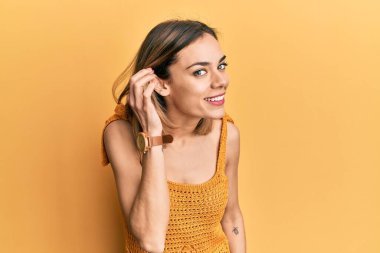 Sarı günlük tişört giyen, kulağı kulağında gülümseyen, dedikoduları ve dedikoduları dinleyen beyaz bir kadın. Sağırlık kavramı. 