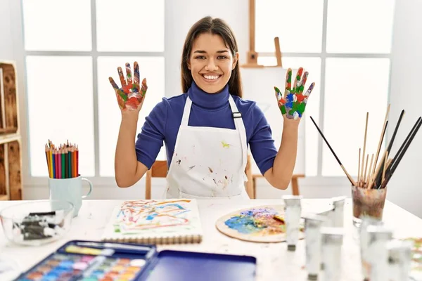 在艺术工作室里 年轻的黑发女人 手绘着彩绘 脸上挂着快乐而清凉的笑容 幸运的人 — 图库照片