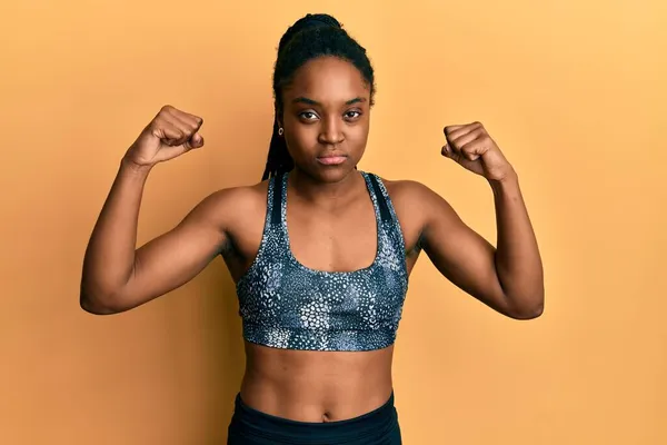 Mujer Afroamericana Con Cabello Trenzado Usando Ropa Deportiva Mostrando Músculos —  Fotos de Stock