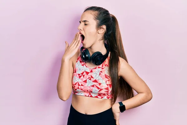 Joven Adolescente Morena Usando Ropa Gimnasio Usando Auriculares Aburridos Bostezando —  Fotos de Stock