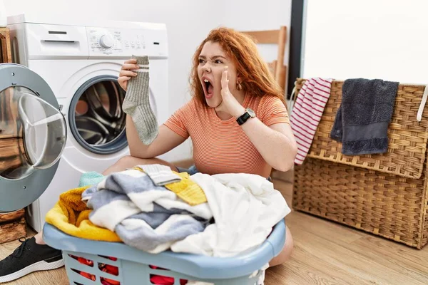 若い赤毛の女性は汚れた洗濯機の叫びに汚れた洗濯機を入れ 口の上で手で大声で叫ぶ コミュニケーションの概念 — ストック写真