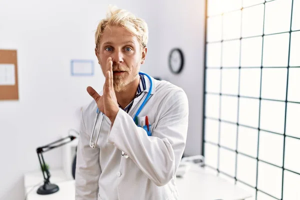 Jonge Blonde Man Draagt Doktersuniform Stethoscoop Kliniek Hand Mond Vertellen — Stockfoto
