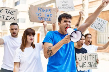 Bir grup genç aktivist ellerinde bayrak, ellerinde megafonla şehri protesto ediyorlar..
