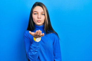 Balıkçı yaka kazak giyen genç esmer kız kameraya bakıp havada bir öpücük savuruyor ve güzel ve seksi oluyor. aşk ifadesi. 