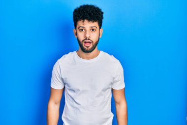 Sakallı, sıradan beyaz tişörtlü genç bir Arap. Şaşırmış ve şaşırmış bir ifade, korku ve heyecanlı bir yüz.. 