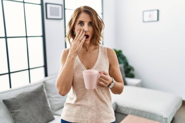 Orta yaşlı bir kadın evde kahve içiyor. Korkmuş ve şok olmuş, şaşırmış ve şaşırmış bir halde. 