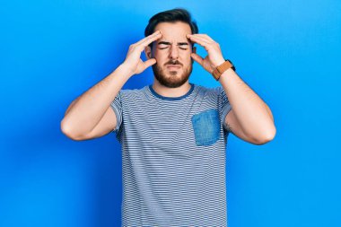 Yakışıklı, sakallı, sıradan çizgili tişörtlü, başı ağrıyan bir beyaz adam. migren ağrısı. 