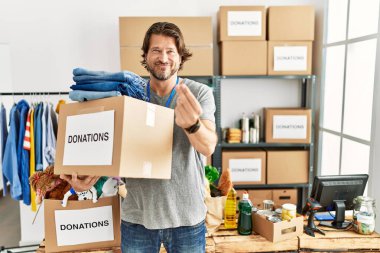 Gönüllü olarak bağış kutusunu tutan yakışıklı orta yaşlı bir adam. Para hareketi yapıyor, maaşını istiyor, milyonerlik işi yapıyor. 