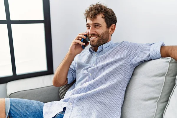 Joven Hombre Hispano Hablando Teléfono Inteligente Sentado Sofá Casa —  Fotos de Stock