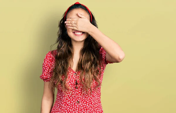 カジュアルな服を着た若いヒスパニック系の女の子が笑顔で 驚きのために目をカバー顔に手で笑っています 視覚障害の概念 — ストック写真