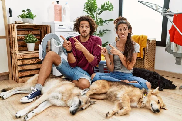 Jovem Casal Hispânico Fazendo Lavanderia Com Cães Apontando Para Lado — Fotografia de Stock