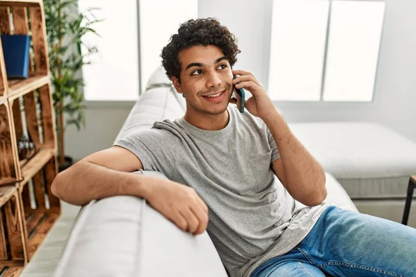 Νεαρός Ισπανόφωνος Μιλάει Στο Smartphone Κάθεται Στον Καναπέ Στο Σπίτι — Φωτογραφία Αρχείου