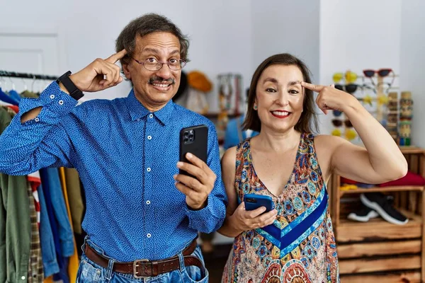 Střední Věk Mezirasový Pár Maloobchodě Pomocí Smartphone Úsměvem Ukazuje Hlavu — Stock fotografie