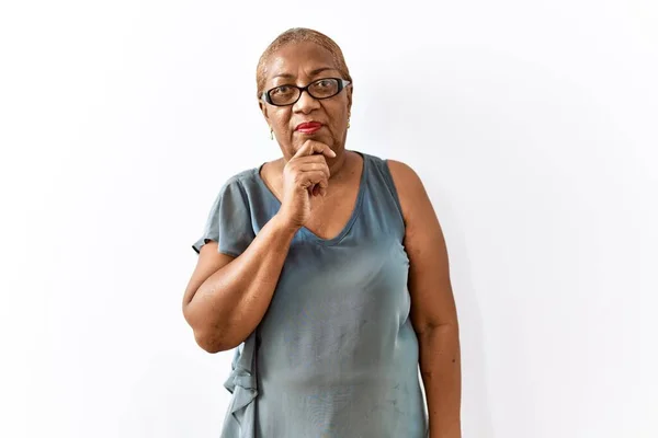 stock image Mature hispanic woman wearing glasses standing over isolated background thinking worried about a question, concerned and nervous with hand on chin 