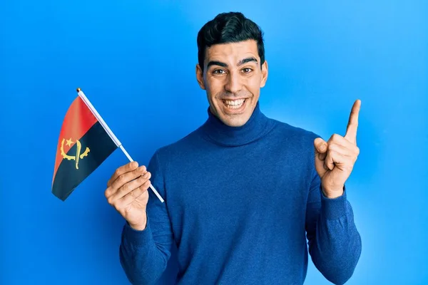 Snygg Hispanic Man Håller Angola Flagga Ler Glad Pekar Med — Stockfoto