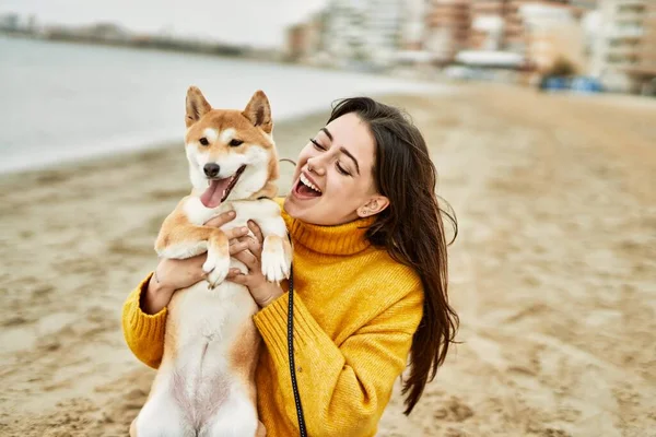 ビーチで幸せな柴犬を抱きしめる美しい若い女性 — ストック写真