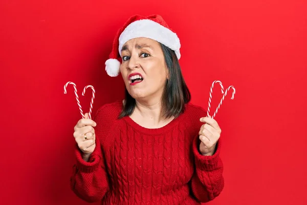 Hispanische Frau Mittleren Alters Mit Weihnachtsmütze Die Bonbons Ahnungslos Und — Stockfoto