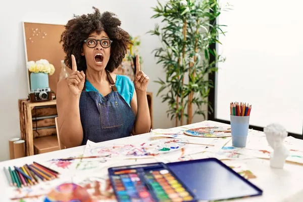 在艺术工作室里 美丽的非洲裔美国女人 有着非洲式的发型 她惊讶地抬起头 用手指和胳膊指指着 — 图库照片