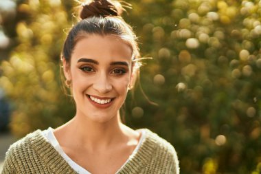 Güzel esmer kadın güler yüzlü mutlu ve kendinden emin sonbaharın güneşli bir gününde şehirde.