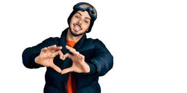 Kar giyen, gökyüzü gözlüğü takan, sırıtan ve elleriyle kalp sembolü yapan İspanyol sakallı genç bir adam. romantik kavram. 