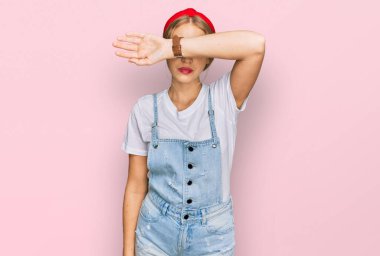 Sıradan kıyafetler giyen, kollarıyla gözlerini kapatan, ciddi ve üzgün görünen beyaz bir kız. Görme, saklama ve reddetme konsepti 