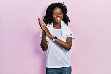 Genç Afro-Amerikalı kadın spor kıyafetleri ve havlu giyip alkışlıyor ve mutlu, neşeli ve gururlu elleri alkışlıyor. 