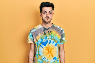 Günlük kıyafetler giyen genç İspanyol adam komik yüzlü yanakları şişiriyor. Havayla şişmiş ağız, çılgın bir ifade.. 