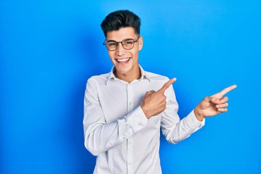 Gündelik kıyafetler giyen, gözlüklü, gülümseyen ve kameraya bakan genç İspanyol bir adam.. 