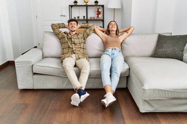 Genç İspanyol çift ellerini başlarının üstüne koyup evdeki kanepede oturuyorlar..