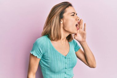 Genç, beyaz, mavi tişörtlü, elleri ağızda bağırıp çağıran sarışın bir kadın. iletişim konsepti. 