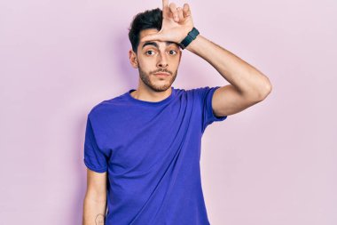 Gündelik tişört giyen genç İspanyol adam alnında parmakları olan insanlarla dalga geçiyor. Ezik hareketler yapıyor, alay ediyor ve hakaret ediyor.. 