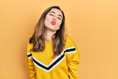 Latin asıllı genç bir kız, gündelik giysiler içinde kameraya bakıyor ve güzel ve seksi bir şekilde havadan öpücük yolluyor. aşk ifadesi. 