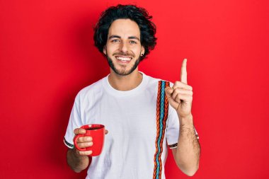 Yakışıklı İspanyol bir adam kahve içiyor bir fikirle gülümsüyor ya da bir soru işareti yapıyor, bir numara: 