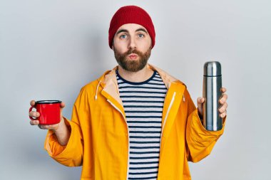 Kafkas sakallı, elinde kahve fincanı olan ve kameraya bakıp öpüşen güzel ve seksi bir adam. aşk ifadesi. 