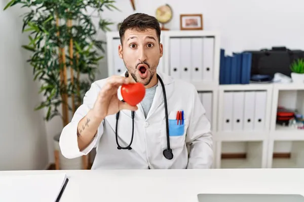 Giovane Medico Che Tiene Cuore Alla Clinica Medica Spaventato Stupito — Foto Stock