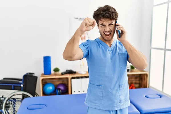 Der Hispanische Physiotherapeut Der Einer Schmerzklinik Arbeitet Telefoniert Genervt Und — Stockfoto