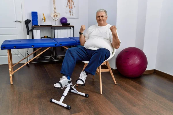 Homem Caucasiano Sênior Clínica Fisioterapia Usando Pedal Exercitador Celebrando Surpreso — Fotografia de Stock