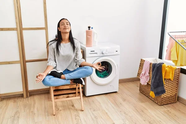 年轻的拉丁女子在洗衣房做瑜伽等洗衣机 — 图库照片