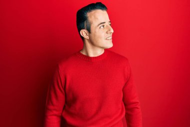 Kış süveteri giyen yakışıklı genç bir adam. Taraf arıyor, rahat bir görünüm takınıyor. Doğal bir yüzü ve kendine güvenen bir gülümsemesi var.. 