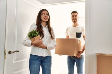 Genç İspanyol çift mutlu bir şekilde gülümsüyor. Karton kutular yeni evlerinde taşınıyor..