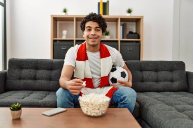 Genç İspanyol adam futbol maçı izliyor ve takımını evde destekliyor..